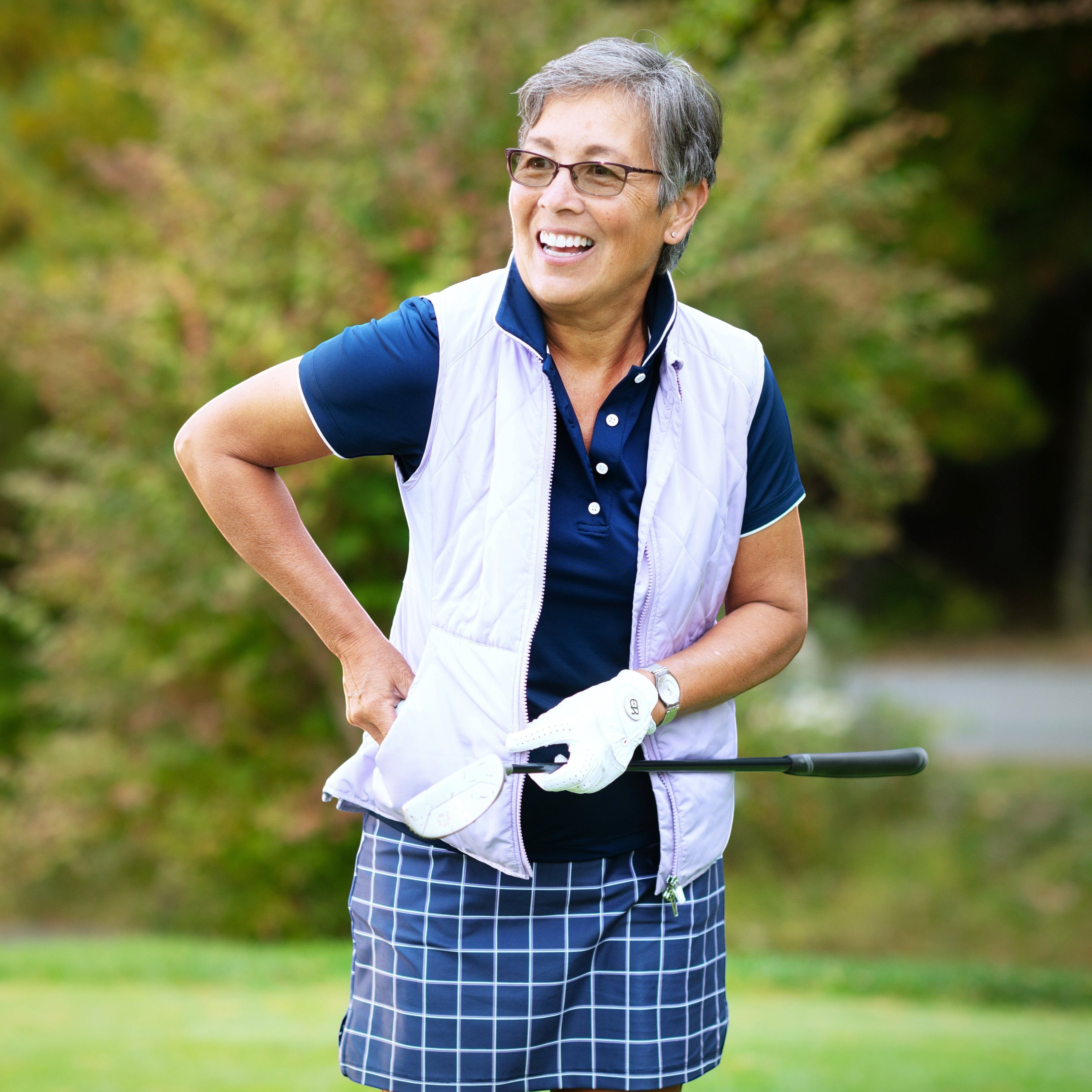 Elliott & Rose navy performance golf polo shirt with white trim, paired with a light purple vest and plaid skirt.