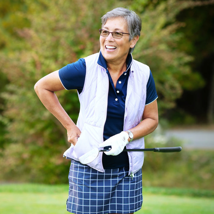 Elliott & Rose navy performance golf polo shirt with white trim, paired with a light purple vest and plaid skirt.
