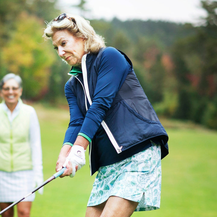 Elliott & Rose navy performance quarter zip pullover with green trim, worn by a woman golfing.