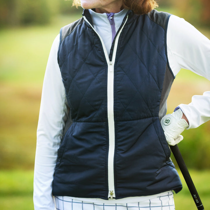 Elliott & Rose navy quilted golf vest with white zipper and side panels, designed for warmth and flexibility.